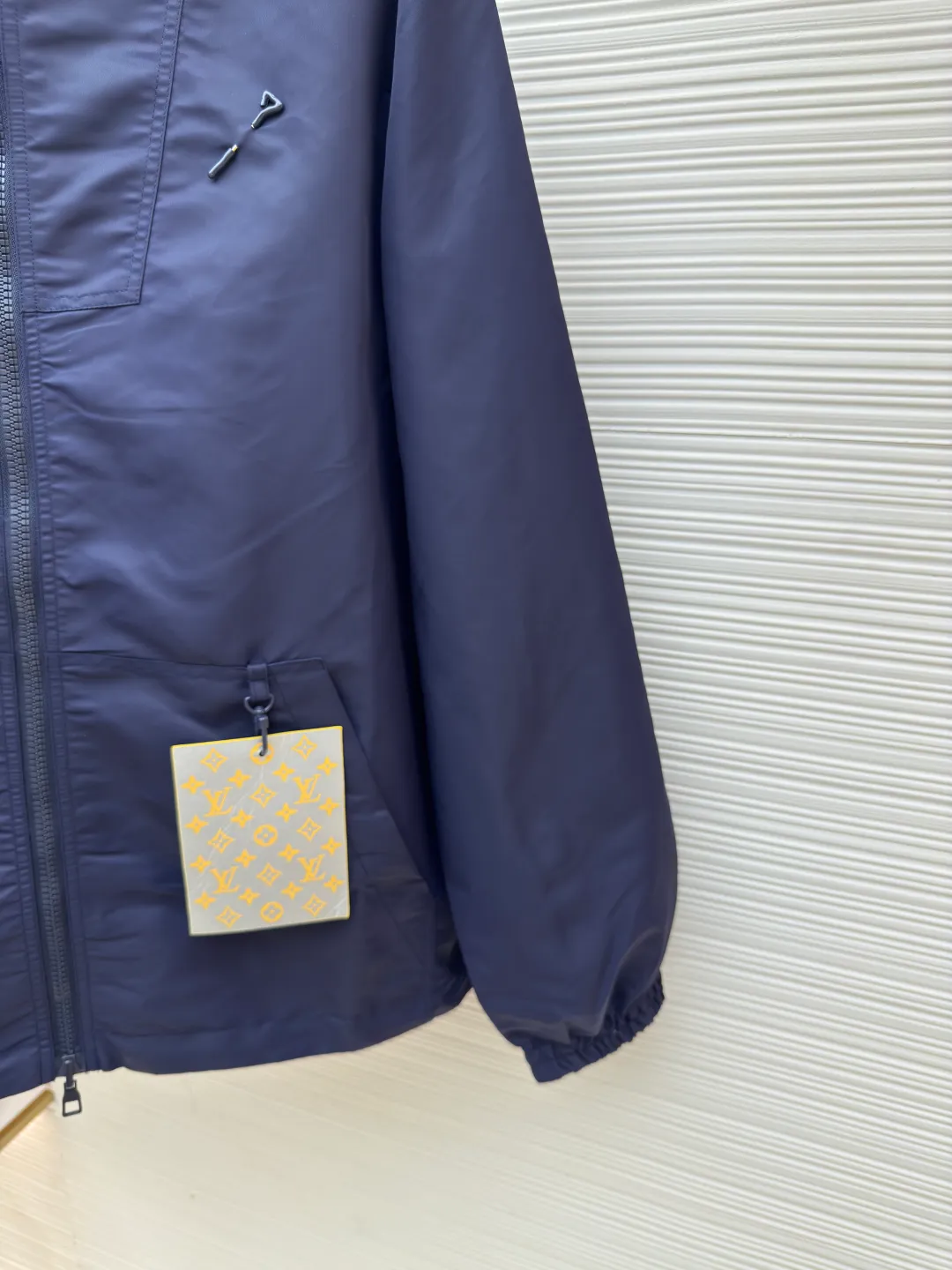 LOUIS VUITTON double-sided windproof pin jacket ●Authentic product: 23000 purchased and developed ●Item number: 1680475-C55 ●Fabric: polyester fiber fabric ●Technology: jacquard ●Version: fitted version ●Weight: about 555 grams ●Size: 44-46-48-50 ●Description: The solid color fabric is made of nylon encrypted matt twill fabric, and the jacquard fabric on the other side is made of 50D nylon yarn-dyed jacquard fabric. The solid color front panel is laser-burned, hand-made of white copper, with a triangle pin with logo and glossy finish. The front panel pocket uses a hardware keychain to hang a folding clothing tag, and the jacquard letters on the front chest placket are made of single-piece flowing pure It is cut by hand to restore the flower, and all the pieces are numbered. The pockets are also cut with the restored flower number. The fabric is relatively light and silky, and it takes time to cut accurately. The front and center are equipped with a double-circulation puller 5# orbital zipper. The hem and the hood are worn with spiral elastic ropes with ring anti-slip buckles, square pig nose buckles with logo, and all holes are punched with hardware and logo on the cloth-colored cornrows.